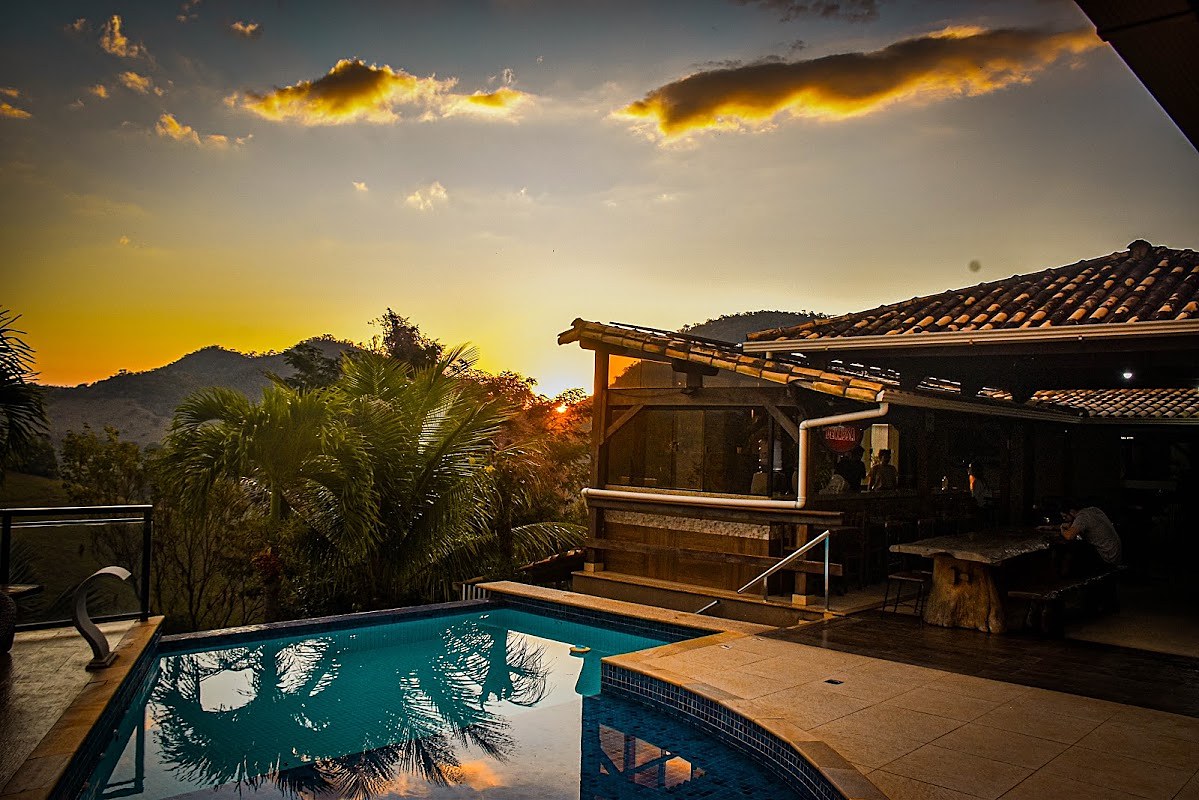 Piscina e restaurante da Pousada Valle do Sol ao pôr do sol, com a serra ao fundo